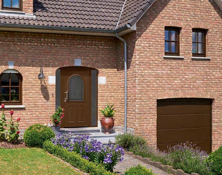Haus mit brauner Tür und Fenster sowie einem Garagenrolltor in derselben Farbe, zeigt einheitliches Design.