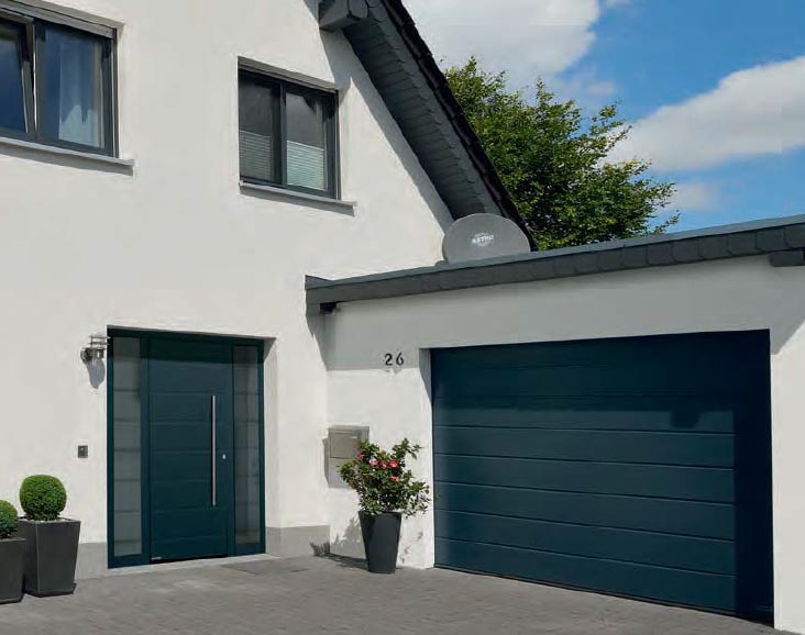 Modernes Haus mit dunkelgrüner Haustür und passender Garage, unterstreicht Eleganz.