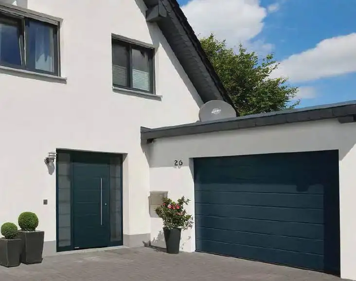 Modernes Haus mit dunkelblauem Sektionaltor und Tür im selben Design von Almtor